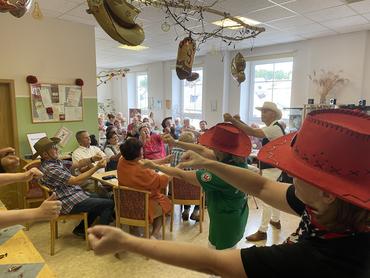 Auf dem Bild sind viele Gäste des Sommerfestes sowie die Line Dancer zu sehen. Die Stimmung ist ausgelassen. 