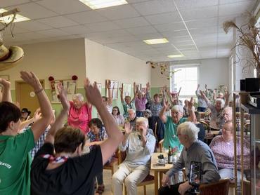 Auf dem Bild sind sehr viele Gäste des Festes zu sehen. Einige heben die Hände in die Luft und folgen dem Programm der Line Dancer. 