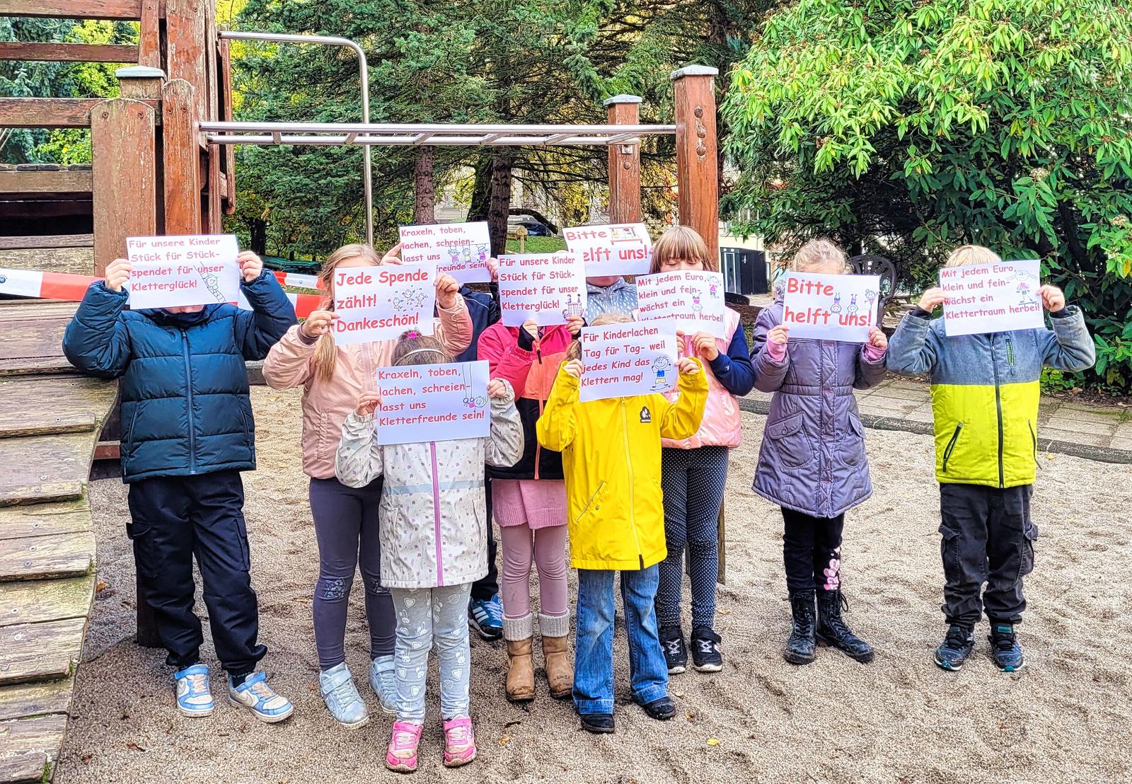 Auf dem Bild sind einige Kinder mit Schildern zu sehen.