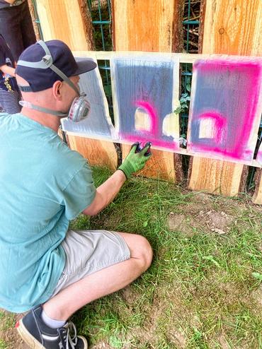 Auf diesem Bild ist ein Künstler zu sehen we3lcher den Zaun anmalt. 