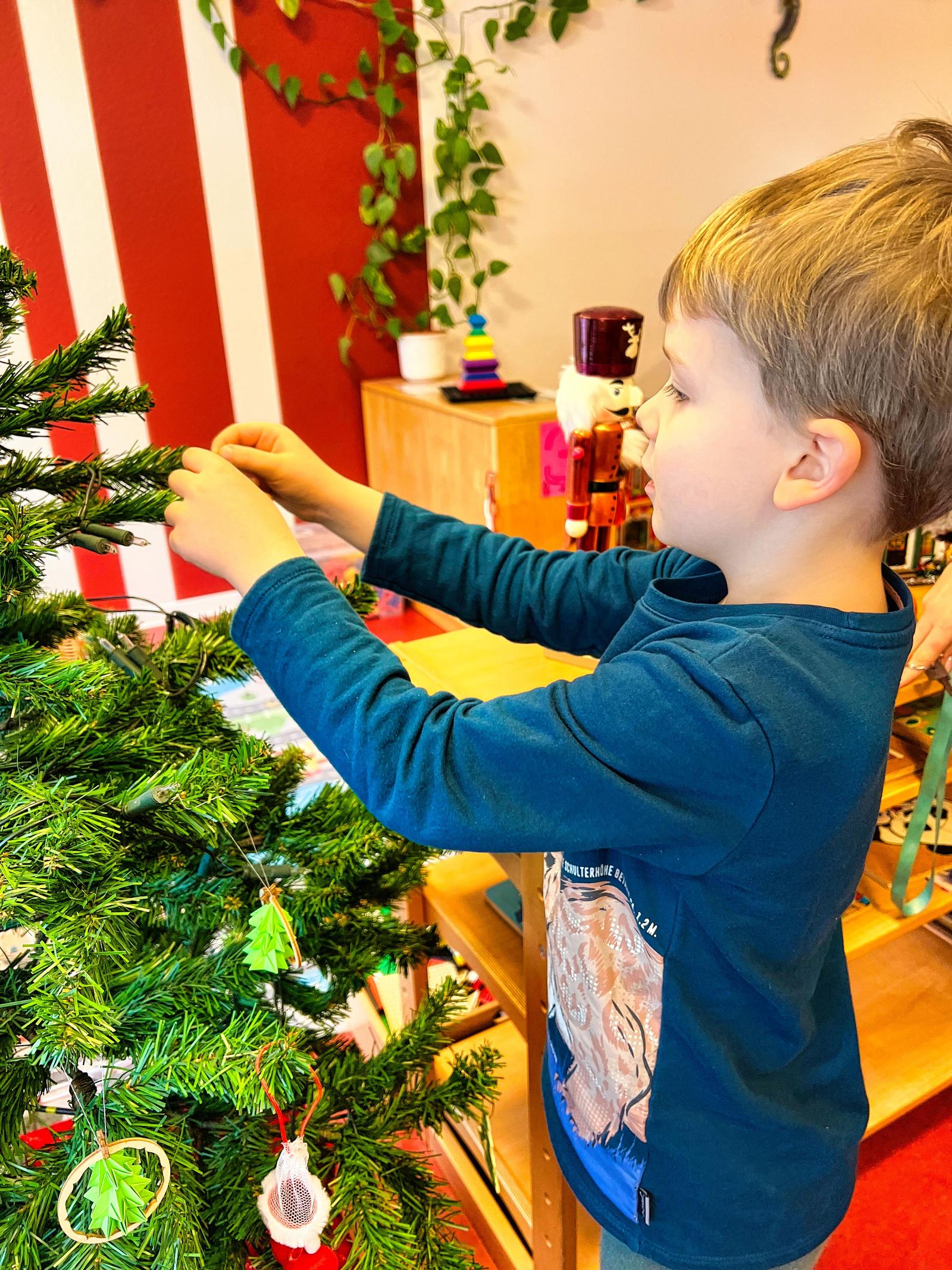 Auf diesem Bild sieht man, wie die Kinder den Baum schmücken.