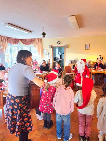 Auf diesem Bild ist der Weihnachtsmann zu sehen. Die Kinder singen Ihm etwas vor und bekommen Geschenke.
