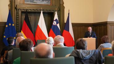 Auf diesem Bild ist der Bürgermeister zus ehen. Er hält eine Rede.