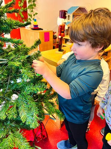 Auf diesem Bild sieht man, wie die Kinder den Baum schmücken.