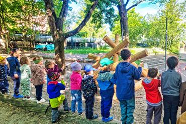 Auf diesem Bild sind viele Kinder des Kindergartens zu sehen. Sie schauen sich gemeinsam das neue Klettergerüst an.