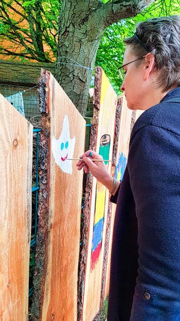 Auf diesem Bild ist unsere Geschäftsführerin Frau Ullrich zu sehen. Sie malt einen Teamgeist auf ein Zaunelement.