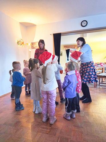 Auf diesem Bild ist der Weihnachtsmann zu sehen. Die Kinder singen Ihm etwas vor und bekommen Geschenke. 
