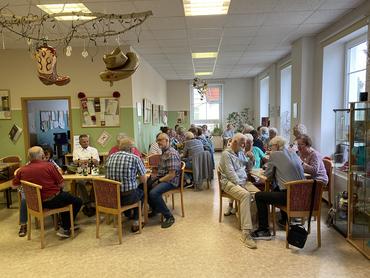 Auf diesem Bild sind einige Gäste des Festes sitzend an Tischen zu sehen. 