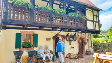 Auf diesem Bild ist ein traditionelles Haus zu sehne. Davor befinden sich einige Teilnehmer der Reise.