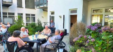 Auf dem Bild sind einige teilnehmer des Festes an den Tischen zu sehen. Die Stimmung ist heiter.