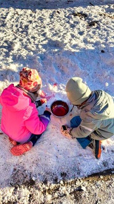 Auf dem Bild sieht man, wie Kinder im Schnee spielen.