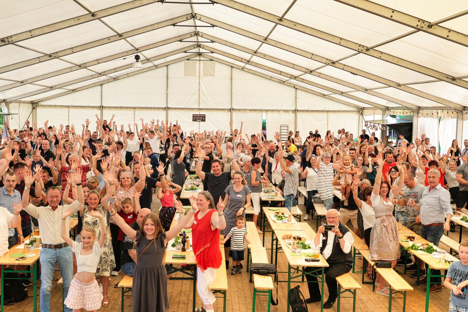 Auf diesem Bild ist eine Großaufnahme von den Besuchern des Festes zu sehen. Viele strecken dabei die Hände freudig in die Luft. 